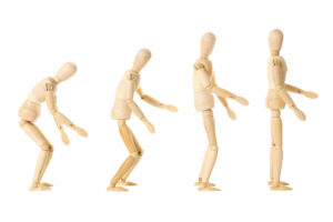 Wooden human figure standing in four positions from upright to slowly hunching forward